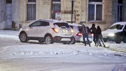 Des personnes poussent une voiture enlisée dans la neige, le 17 janvier 2024, à Ferrière-la-Grande (Nord). (SAMI BELLOUMI / LA VOIX DU NORD / MAXPPP)