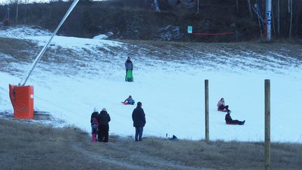 Des enfants&nbsp;font de la luge malgré le manque de neige, le 3 janvier 2019, dans la station de ski du Cambre d'Aze (Pyrénées-Orientales). (RAYMOND ROIG / AFP)