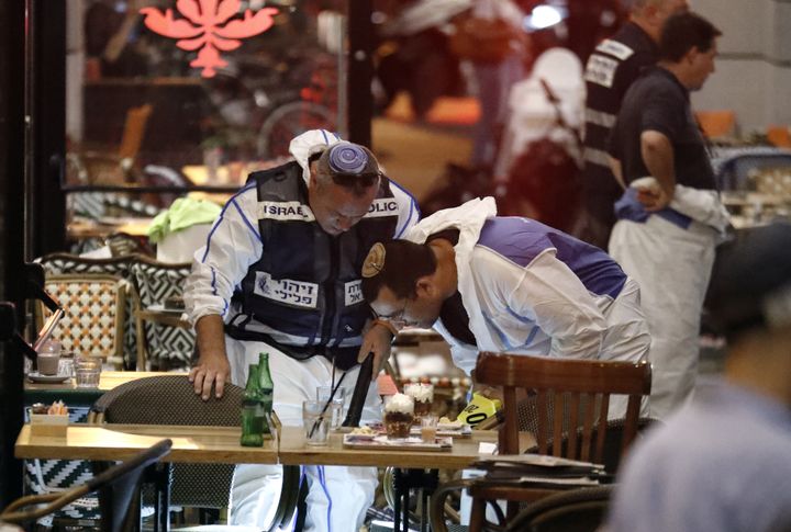 Des policiers israéliens inspectent un restaurant, après une attaque armée qui a fait trois morts, à Tel Aviv, le 8 juin 2016. (JACK GUEZ / AFP)