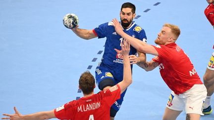 Nikola Karabatic tente de monter plus haut que la défense danoise, à l'occasion de l'Euro 2022 de handball, mercredi 26 janvier. (ATTILA KISBENEDEK / AFP)