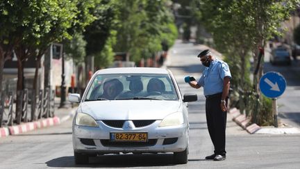 Un policier palestinien contrôle un véhicule, le 3 juillet 2020, en pleine crise sanitaire du coronavirus. (ISSAM RIMAWI / ANADOLU AGENCY)