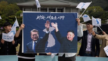 Des militants en faveur de la paix&nbsp;brandissent&nbsp;une photo montrant&nbsp;le président sud-coréen Moon Jae-in et le dirigeant nord-coréen Kim Jong-un, avec le slogan "un nouveau départ pour la paix",&nbsp;lors d'une manifestation à Séoul, le 26 avril 2018, devant la résidence de Moon Jae-in.&nbsp; (ED JONES / AFP)