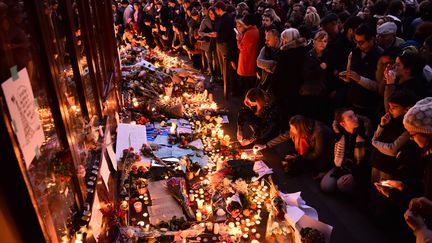 Des fleurs et des bougies sont déposées à la terrasse du bar Le Carillon, le 15 novembre 2015.&nbsp;L'établissement a été visé l'avant-veille par des terroristes ayant mené une série d'attaques coordonnées qui ont fait 130 morts à Paris et Saint-Denis. (LOIC VENANCE / AFP)