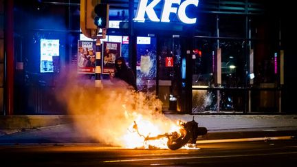 Une moto brûle devant un KFC de Rotterdam, aux Pays-Bas, après une manifestation contre l'instauration du couvre-feu, le 25 janvier 2021. (MARCO DE SWART / ANP)