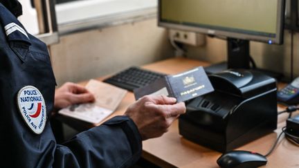 Un policier français tient un passeport à l'entrée du tunnel sous la Manche, à Calais (Pas-de-Calais), le 31 janvier 2020. Photo d'illustration. (DENIS CHARLET / AFP)