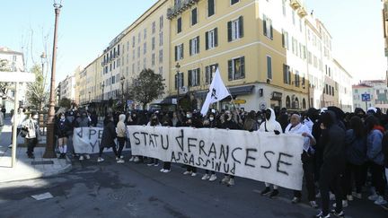 Des lycéens tiennent une banderole sur laquelle est écrit en corse "Etat français assassin", lors d'une manifestation organisée le 10 mars 2022 à Ajaccio (Corse-du-Sud), après la tentative d'assassinat d'Yvan Colonna. (PASCAL POCHARD-CASABIANCA / AFP)