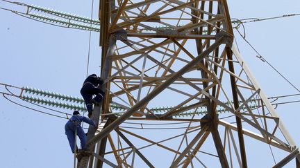 Des techniciens de la Compagnie nationale d'électricité réparent les lignes à haute tension endommagées par les combats au sud de Tripoli, le 23 mai 2019. (MAHMUD TURKIA / AFP)