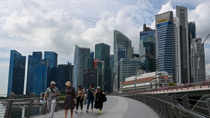 Des passants sur le pont du Jubilé sur le front de mer de Singapour, le 17 novembre 2023. (ROSLAN RAHMAN / AFP)