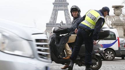 Un policier contr&ocirc;le la plaque d'immatriculation d'un scooter, le 17 mars 2014 &agrave; Paris alors qu'une mesure de circulation altern&eacute;e a &eacute;t&eacute; prise. (FRANCOIS GUILLOT / AFP)