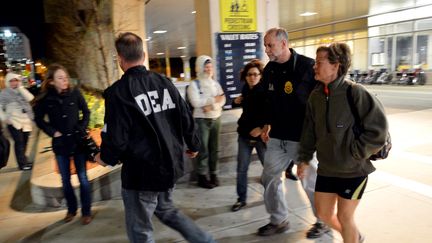 Une femme est accompagn&eacute;e par des agents de la DEA, &eacute;quivalent de la brigade des stup&eacute;fiants, &agrave; l'entr&eacute;e d'un h&ocirc;pital du Brigham and Women's Hospital, le 15 avril&nbsp;&agrave; Boston (Massachusetts, Etats-Unis).&nbsp; (STAN HONDA / AFP)