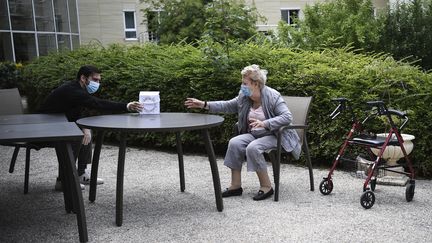 Une femme recevant un cadeau de son petit-fils dans un Ehpad de Saint-Maur-des-Fossés (Val-de-Marne) en juin 2020. (ANNE-CHRISTINE POUJOULAT / AFP)