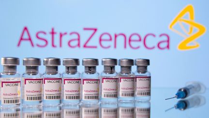 Des flacons étiquetés "AstraZeneca Coronavirus Covid-19 Vaccine" et une seringue devant un logo de l'entreprise pharmaceutique AstraZeneca&nbsp;le&nbsp;14 mars 2021. (DADO RUVIC / REUTERS)