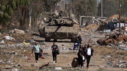 Des Palestiniens fuyant le nord de la bande de Gaza passent devant des chars de l'armée israélienne le 24 novembre 2023. Après l'attaque du 7 octobre, le Premier ministre israélien, Benyamin Nétanyahou, a promis la destruction du Hamas. Le 28 décembre, le ministère de la Santé du Hamas a affirmé que les opérations militaires israéliennes dans l'enclave palestinienne avaient fait 21 320 morts depuis le début de la guerre. (MAHMUD HAMS / AFP)