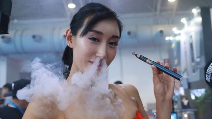 Une&nbsp;démonstratrice fume une cigarette électronique lors d'une salon d'exposition, le 23 juillet 2015 à Pékin (Chine). (AFP)