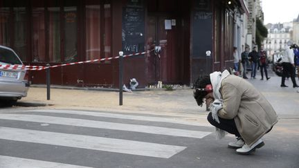 Une femme se recueille devant le Carillon. (KENZO TRIBOUILLARD / AFP)