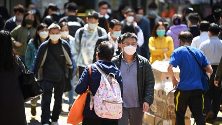 Des passants portent le masque dans les rues de Hong Kong, le 27 février 2023. (PETER PARKS / AFP)