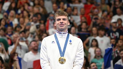 Le Français Léon Marchand savoure, la médaille d'or autour du cou, après un troisième sacre olympique glané sur le 200 m brasse, le 31 juillet 2024, à Paris La Défense Arena. (JONATHAN NACKSTRAND / AFP)