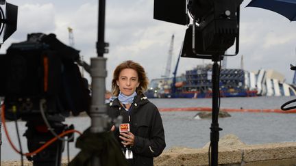 Une journaliste devant l'&eacute;pave du Costa Concordia, le 16 septembre 2013 sur l'&icirc;le du Giglio (Italie). (ANDREAS SOLARO / AFP)