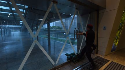 Un vigile barricade les portes d'un immeuble du centre de Hong Kong, mercredi 23 août, avant l'arrivée du typhon Hato. (ANTHONY WALLACE / AFP)