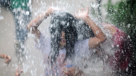 Des enfants jouent sous une goutti&egrave;re apr&egrave;s une averse &agrave; Manille aux Philippines, le 20 juillet 2012. (NOEL CELIS / AFP)