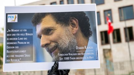 Une photo d'Osman Kavala brandie devant l'ambassade de Turquie en Allemagne à Berlin, le 15 octobre 2020. (CHRISTOPHE GATEAU / DPA)