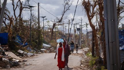 Des femmes rescapées du cyclone Chido à Mayotte de retour de leur quête d'eau à Pamandzi, le 17 décembre 2024. (DIMITAR DILKOFF / AFP)