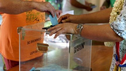 A voter casts a ballot in the ballot box during the first round of legislative elections in Hakahau, French Polynesia, on June 29, 2024. (SYLVAIN LEFEVRE / HANS LUCAS / AFP)