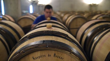 Un employ&eacute; contr&ocirc;le les barriques de vin dans le cellier des Hospices de Beaune (C&ocirc;te-d'Or), le 21 octobre 2014. Une cit&eacute; des vins de Bourgogne est pr&eacute;vue dans la ville &agrave; l'horizon 2017. (PHILIPPE DESMAZES / AFP)