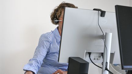 Une femme au téléphone devant son écran d'ordinateur. (PICTURE ALLIANCE / PICTURE ALLIANCE / GETTY IMAGES)