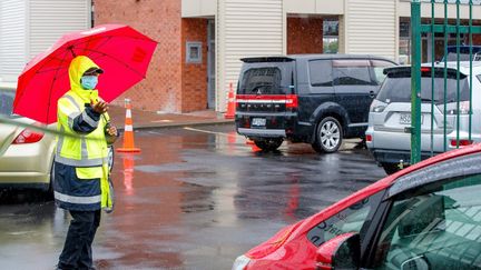 Un agent de sécurité contrôle les automobilistes en attente d'un test de dépistage&nbsp;au lycée de Papatoetoe (Nouvelle-Zélande), le 15 février 2021. (DAVID ROWLAND / AFP)