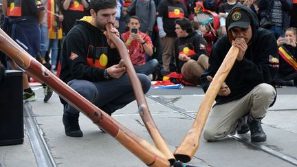 instrument traditionnel aborigène, participent à la semaine de NAIDOC (National Aboriginal and Islander Day Observance Committee - Comité d'Observance des Aborigènes et Insulaires), ici à Melbourne. Les Aborigènes australiens sont les premiers occupants de l'île-continent, les «insulaires» sont, quant à eux, les habitants initiaux des îles du détroit de Torrès (l'archipel se trouvant entre l'Australie et la Nouvelle-Guinée Papouasie). 

	Après avoir tenté, et presque réussi, à faire disparaître ces populations autochtones par absorption biologique (couper les enfants de leurs parents et les placer, loin, dans des familles blanches), l'Australie les met maintenant à l'honneur, leur rend hommage et reconnaît la qualité et la pertinence de leurs différents savoirs ancestraux. 


	La thématique de la cuvée 2016 est « Le temps des rêves », ce chant qui désigne l’ère qui précède la création de la Terre dans les croyances anciennes aborigènes.   

	Le Ministre de la Police, Bill Byrne a expliqué son opinion sur cette semaine, « qui se déroule du 3 juillet au 10 juillet qui est un moment important qui permet d’embrasser et de célébrer la culture et les accomplissements des premiers australiens ». 

 (Recep Sakar / Anadolu Agency)