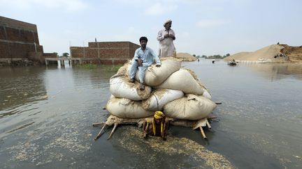 Des victimes des inondations utilisent une barge de fortune pour transporter du foin pour le bétail, à Jaffarabad, dans le district du Balouchistan,&nbsp;le 5 septembre 2022. (FAREED KHAN / AP / SIPA)