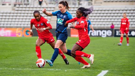 La Parisienne Gaëtane Thiney au duel avec deux joueuses de Fleury, lors du quart de finale de Coupe de France entre le Paris FC et le FC Fleury 91, le 5 mars 2022 au stade Charléty.&nbsp; (MELANIE LAURENT / A2M SPORT CONSULTING / DPPI via AFP)