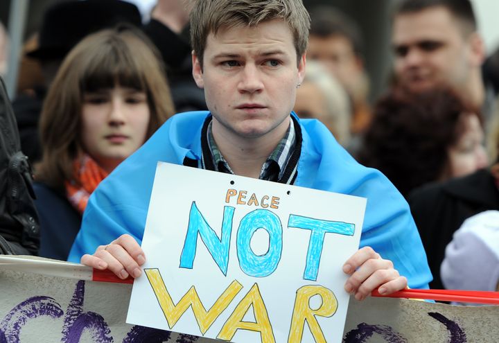 Un manifestant tient une pancarte pacifiste, lors d'une manifestation devant l'ambassade russe &agrave; Berlin (Allemagne), le 2 mars 2014. (BRITTA PEDERSEN / DPA)